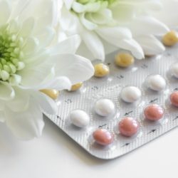 close up of contraceptive pills and daisies